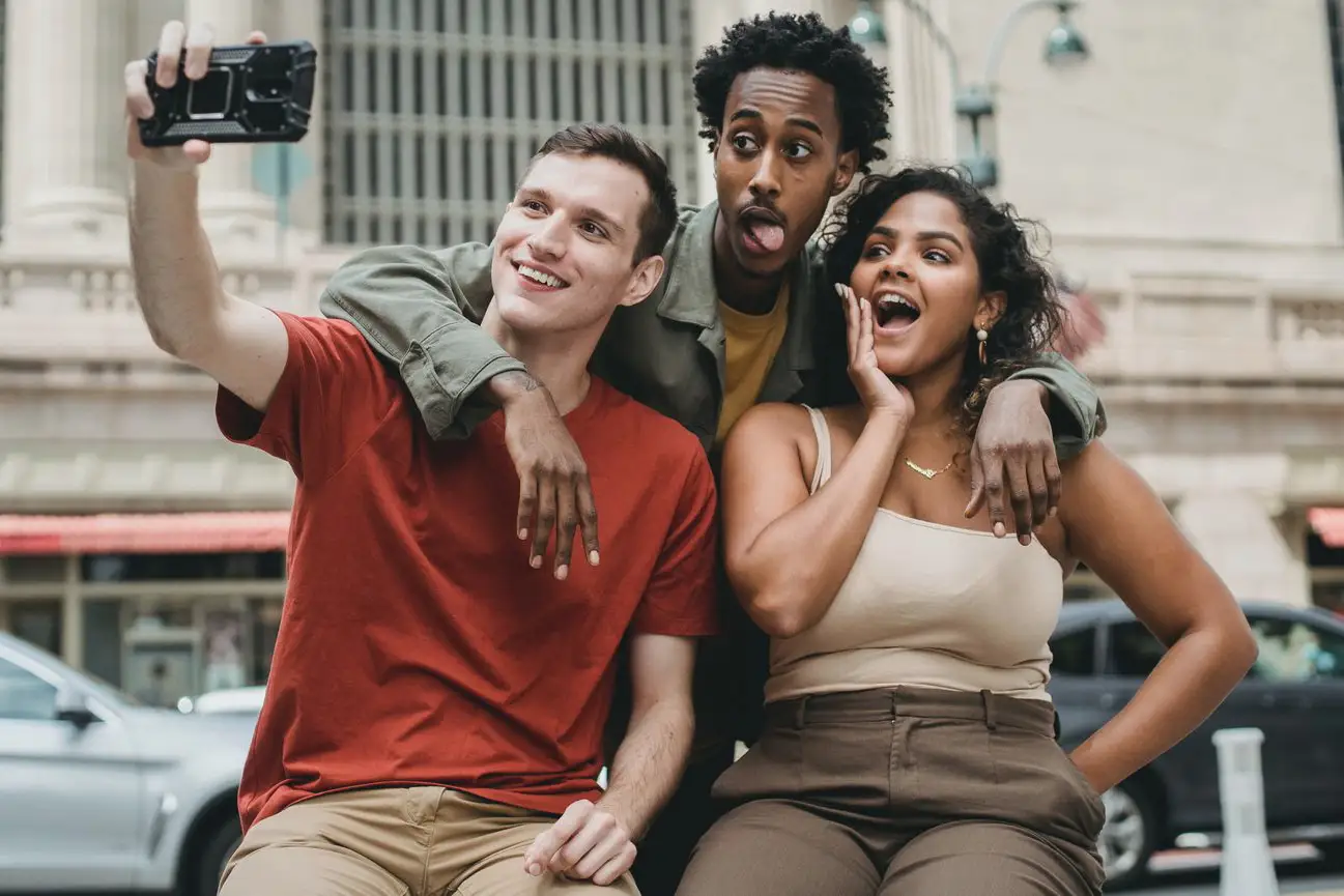 Amis multiethniques en train de prendre un selfie drôle dans la rue.